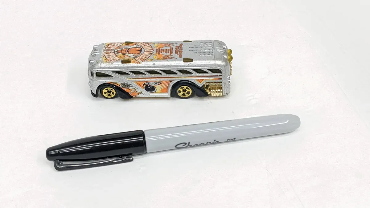This is a 1987 Matchbox Pontiac Grand Am in Neon Tangerine with authentic reproduction factory decals and a slightly bent right-side mirror from aggressive track use.