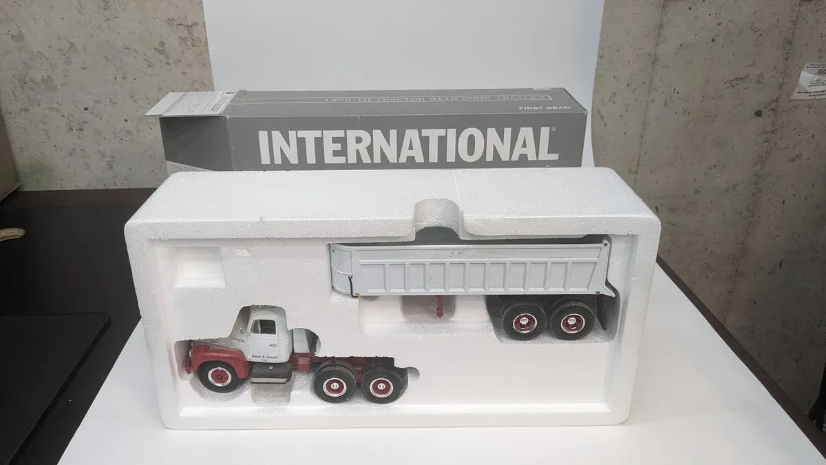 This is a meticulously detailed 1:64 scale replica of a 1987 Peterbilt 379 with a working hydraulic dump bed system and dual rear axles.
