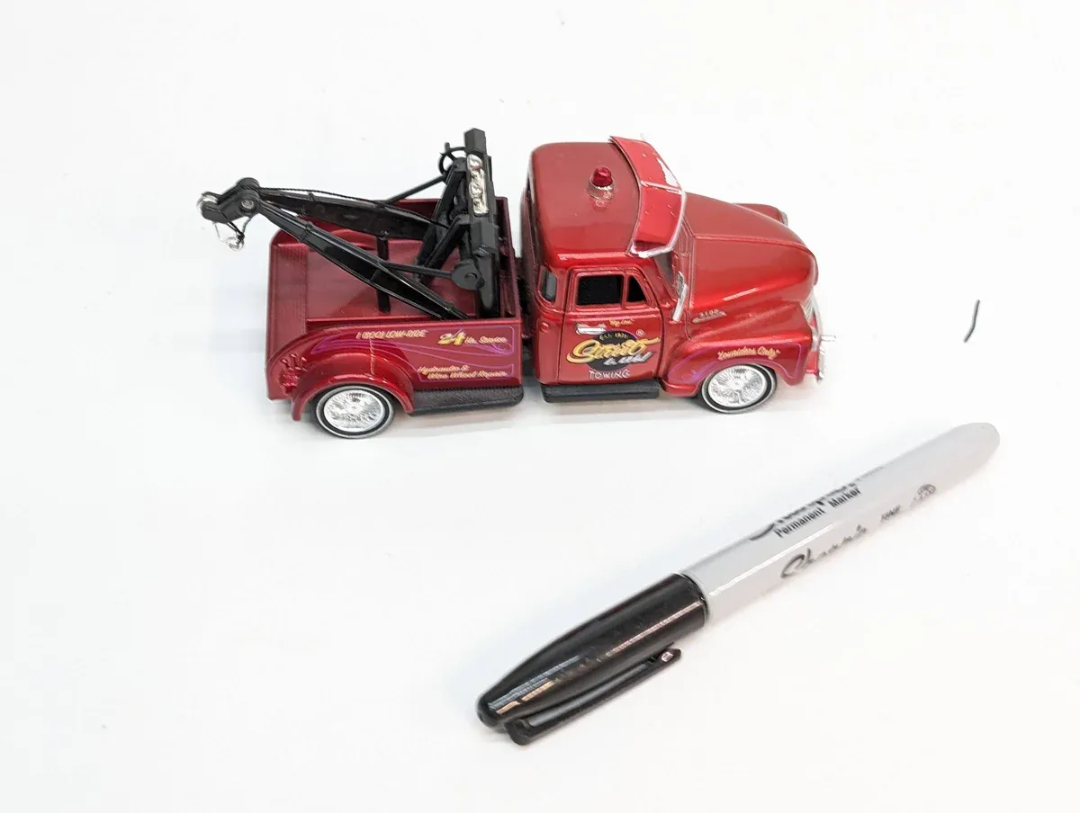 This is clearly a 1947 International Harvester KB-5 light-duty wrecker with non-original aftermarket grille modifications and a hastily welded boom assembly.